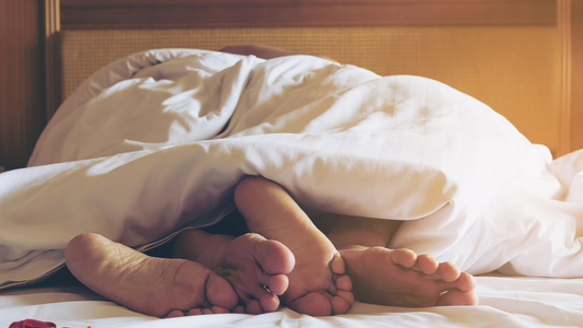 2 pairs of feet in bed in white sheets