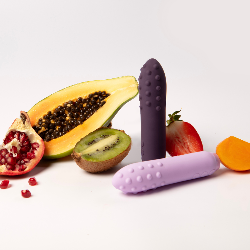 Two Je Joue vibrators in front of various fruits 